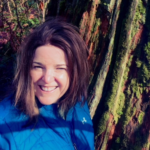 Headshot of Kathleen in front of a tree wearing blue